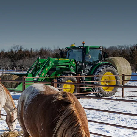 tractor on a farm with horses in the snow